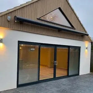 A white house with a black roof and glass doors.