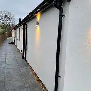 A white building with a black pipe on the side of it.