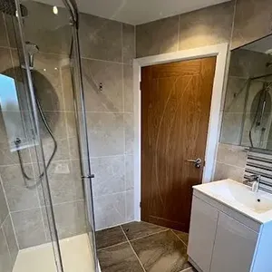 A bathroom with a walk in shower next to a sink.