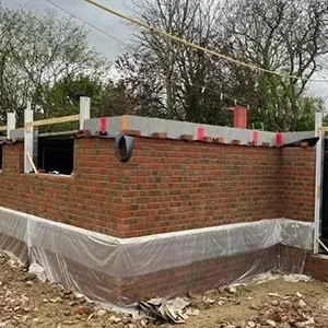 A brick house under construction with a tarp covering it.