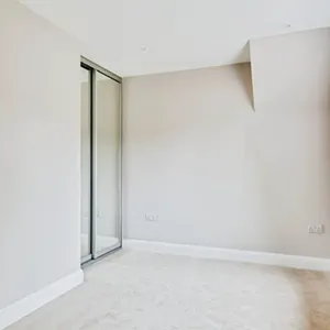 An empty room with white walls and a sliding glass door.