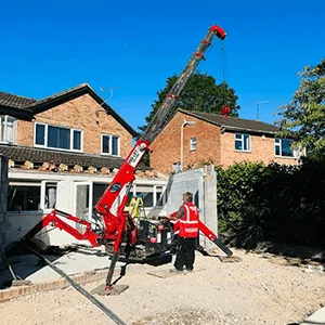 a man standing next to a crane in front of a house