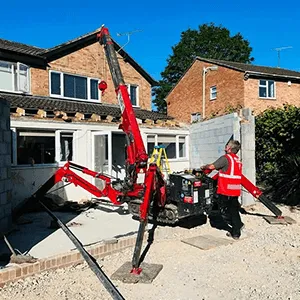 a man standing next to a red machine in front of a house